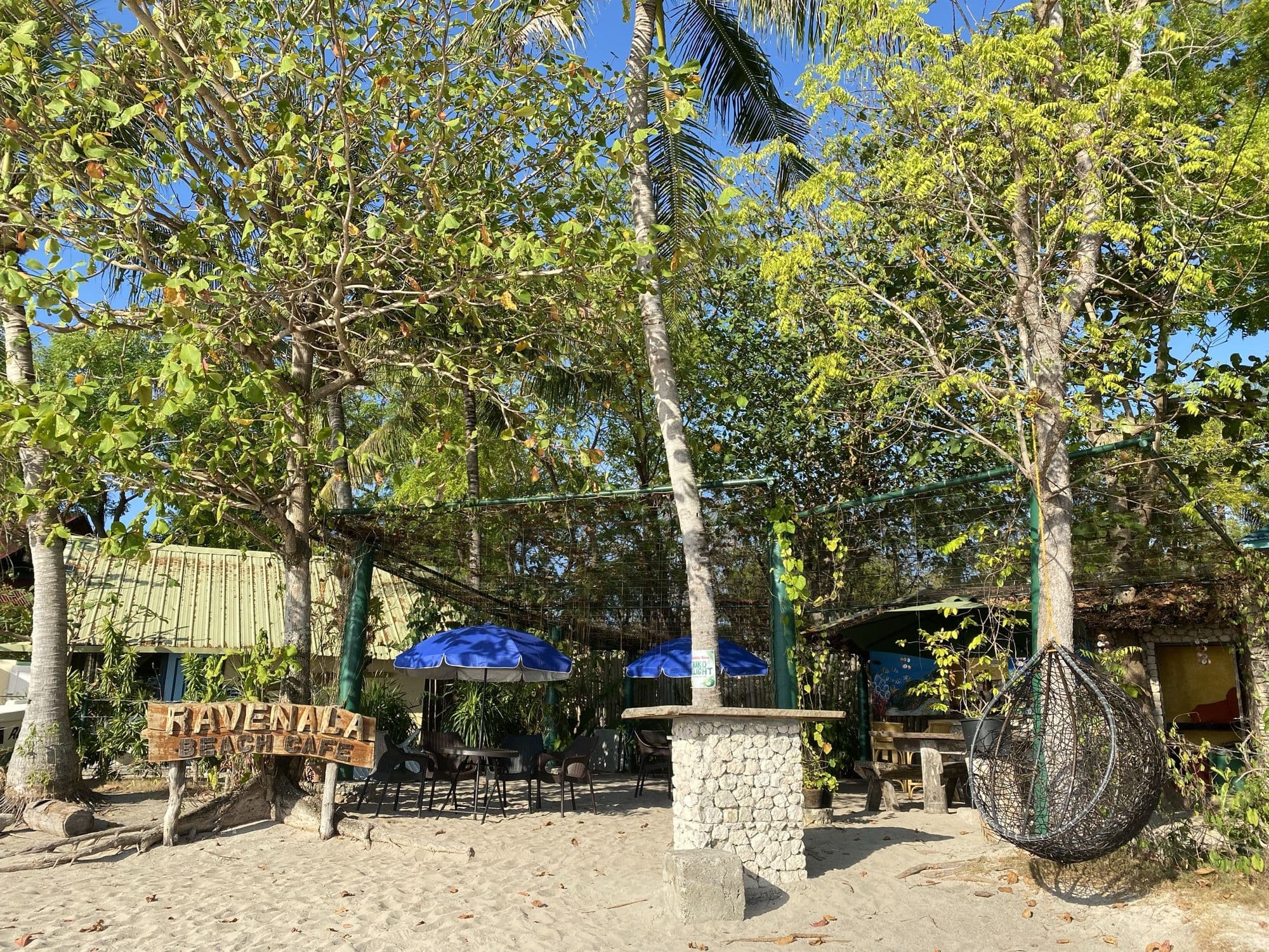 The Ravenala Beach Cafe sign and shaded tables on White Beach