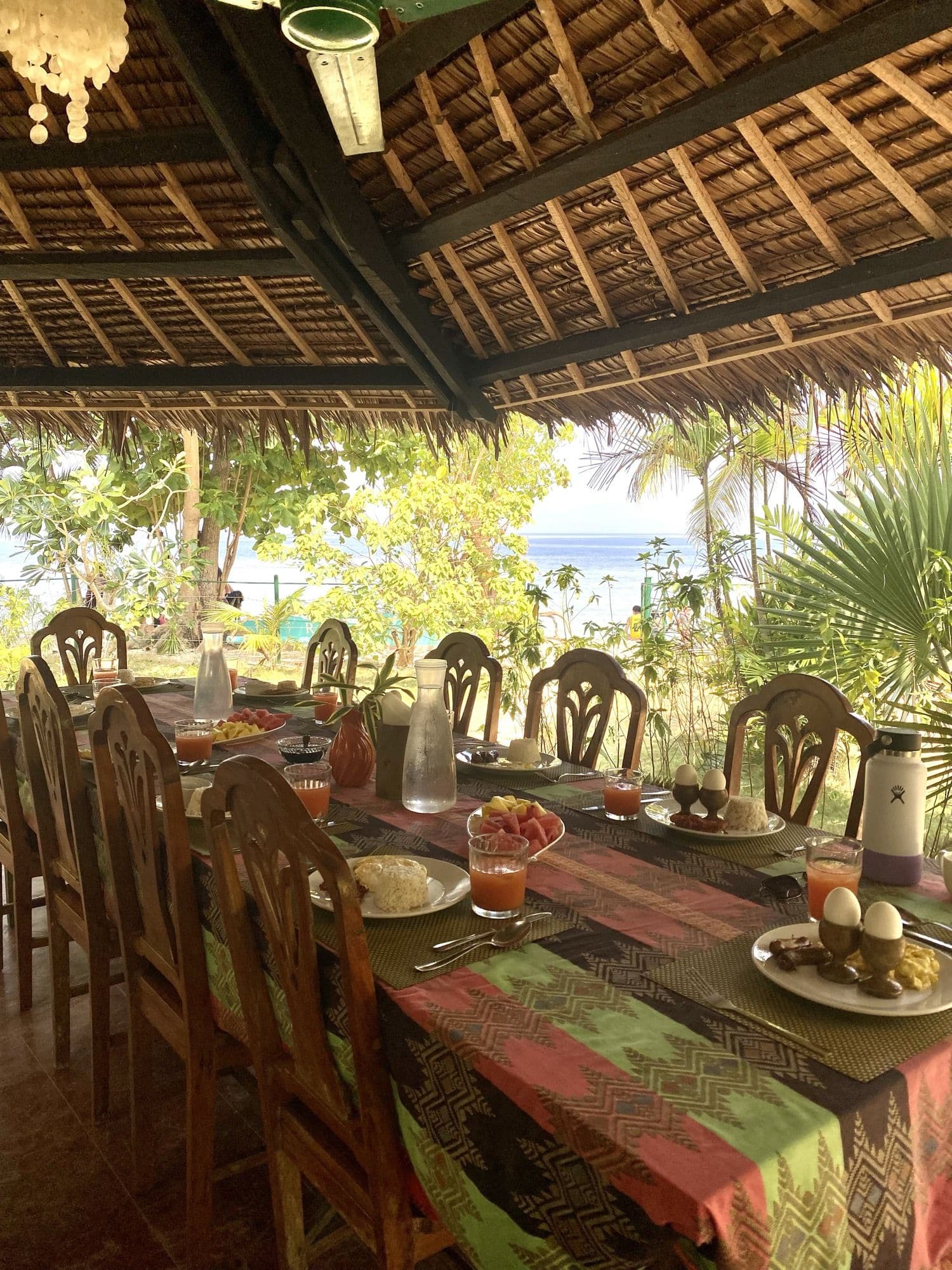 The long dining table set beneath the thatched roof